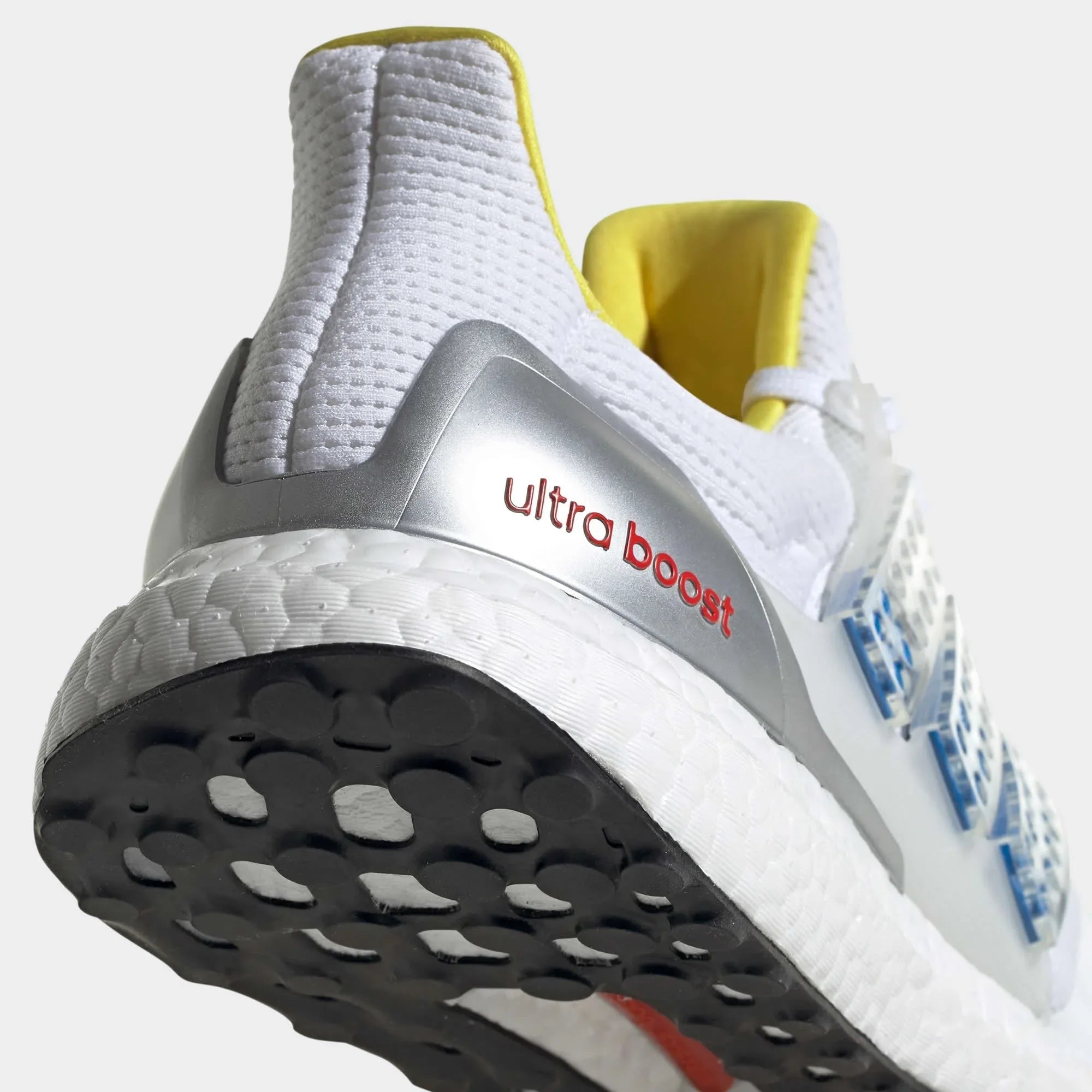 Detailed zoom on the outsole and midsole of the Adidas Ultraboost DNA x Lego Men's trainers, highlighting the Boost cushioning pellets and rubber tread.