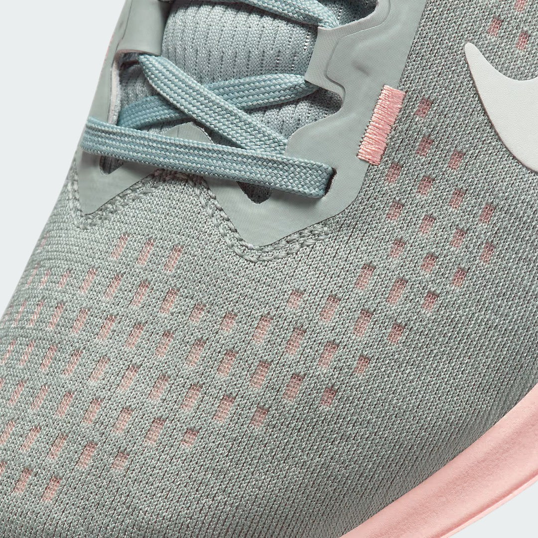 Close-up zoom on the front of the Nike Air Winflo 10 Women's green running shoes, showing the mesh upper texture, lacing system, and synthetic overlays.