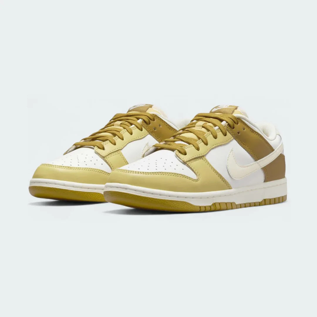 Angled view of two Nike Dunk Low Retro Men's sneakers in bronzine and coconut milk, side by side, showcasing their timeless design and clean aesthetic.