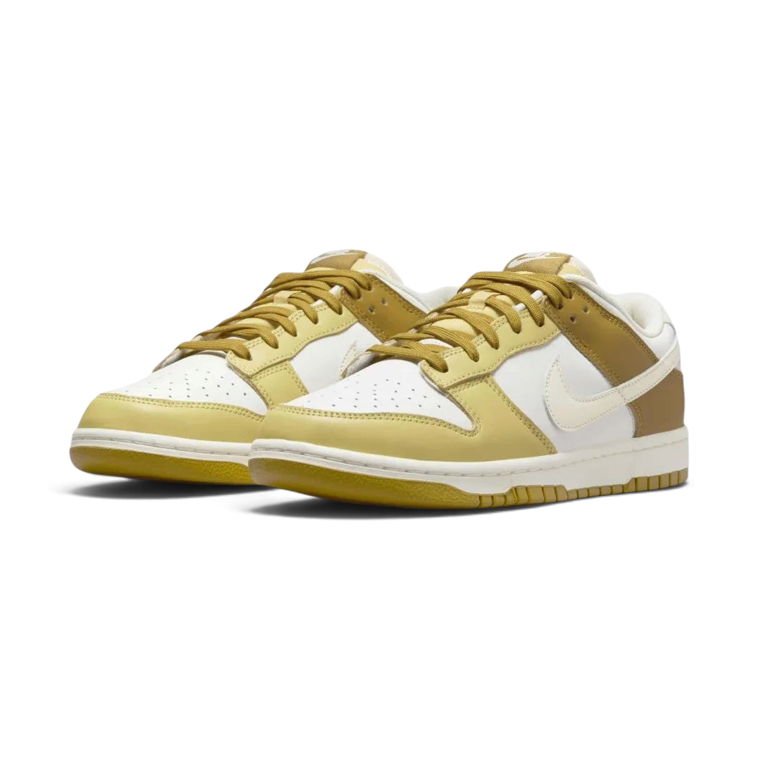 Angled view of two Nike Dunk Low Retro Men's sneakers in bronzine and coconut milk, side by side, showcasing their timeless design and clean aesthetic.
