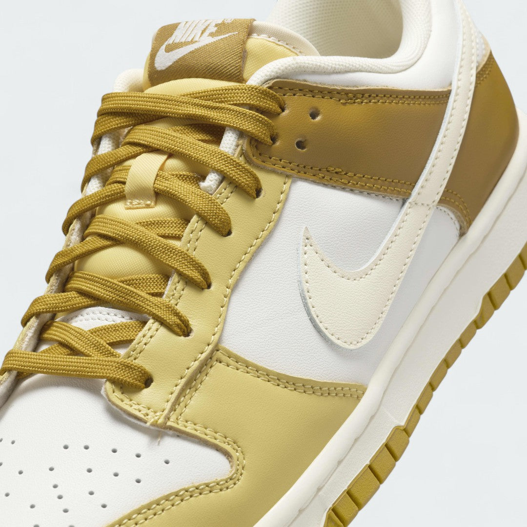 Close-up zoom on the front of the Nike Dunk Low Retro Men's bronze sneakers, showing the perforated toe box, lace-up system, and textured leather upper.