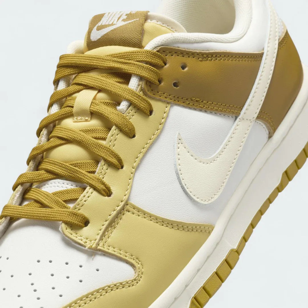 Close-up zoom on the front of the Nike Dunk Low Retro Men's bronze sneakers, showing the perforated toe box, lace-up system, and textured leather upper.