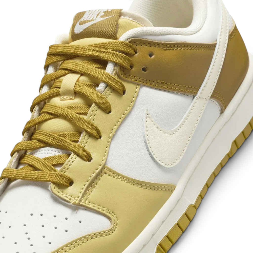 Close-up zoom on the front of the Nike Dunk Low Retro Men's bronze sneakers, showing the perforated toe box, lace-up system, and textured leather upper.
