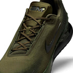 Detailed close-up angle capturing the textured olive mesh upper, tonal laces, and the stylized "AM" tongue badge with neon lime accent.