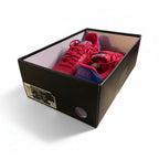 Red sneakers inside a black shoe box on a white background