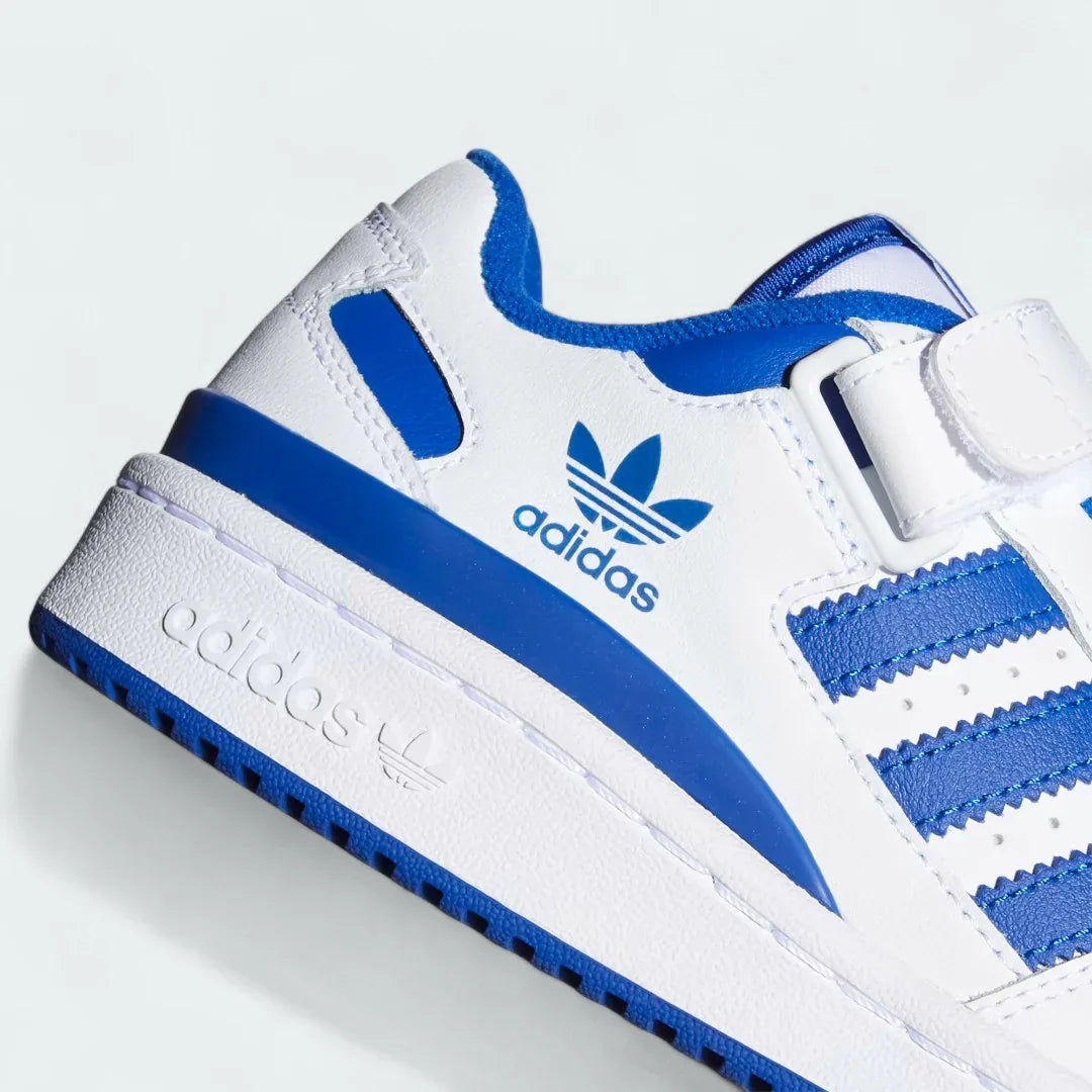Close-up zoom on the front of the Adidas Forum Low Juniors' white trainers, showing the perforated toe box, lace-up system, and X-detail.