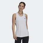 A woman wearing a white Adidas Aeroready D2M racerback tank top with a crewneck.