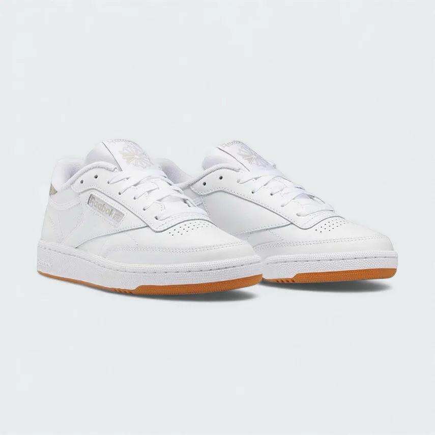 Angled view of two Reebok Classic Club C 85 Unisex white trainers, side by side, showcasing their timeless aesthetic and classic court design.