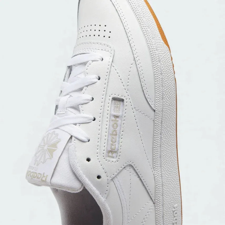 Close-up zoom on the front of the Reebok Classic Club C 85 Women's white trainers, showing the leather texture, perforated toe box, and lacing system.