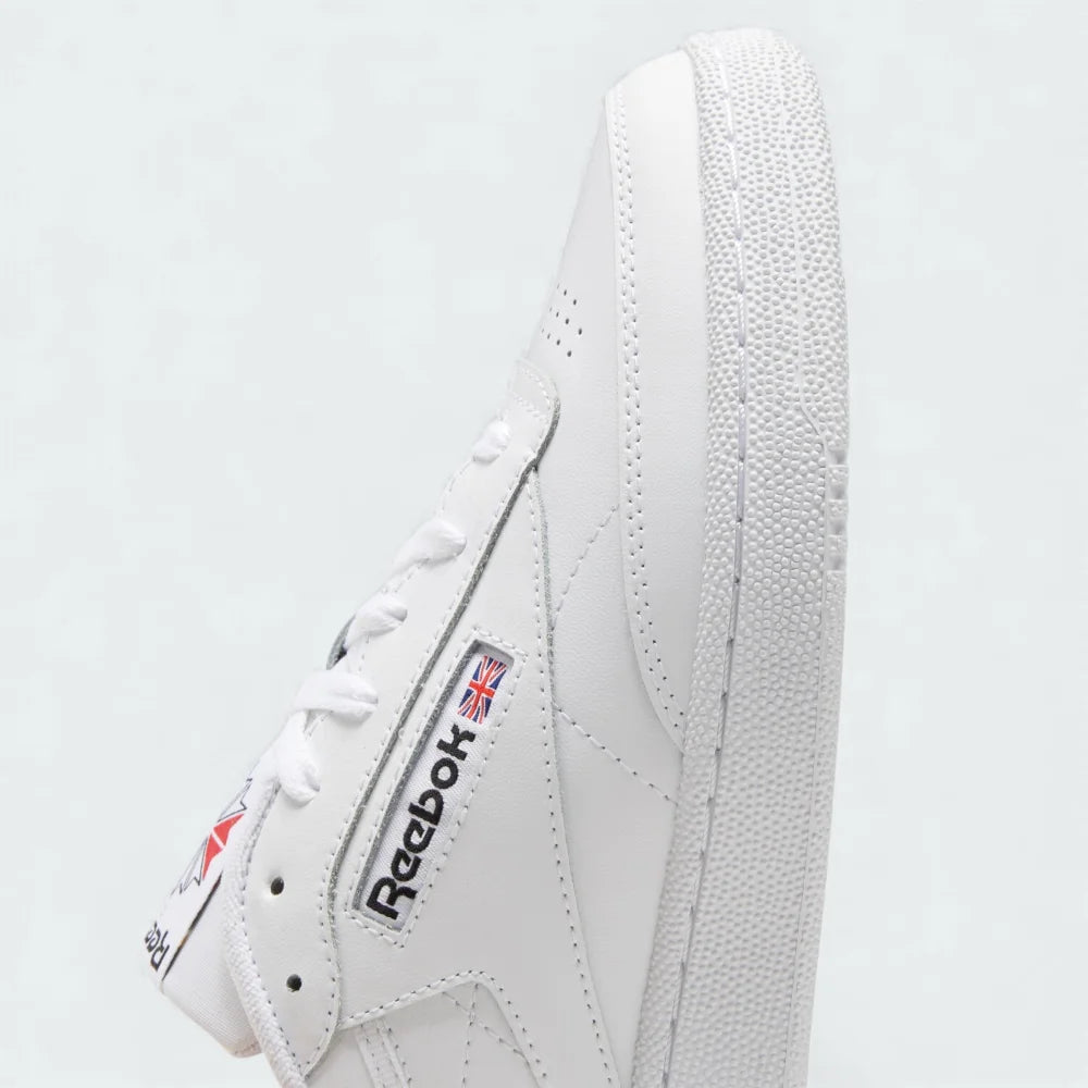 Close-up of the tongue area of the Reebok Club C 85 white trainers, showing the cloud white lacing system, padded tongue, and the woven tag with Core Black Reebok branding.