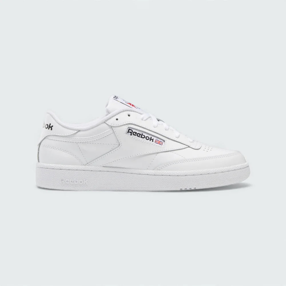 Reebok Classic Club C 85 Unisex trainers in cloud white leather with black accents, side profile showing the iconic low-cut silhouette, cushioned midsole, and Reebok window logo.