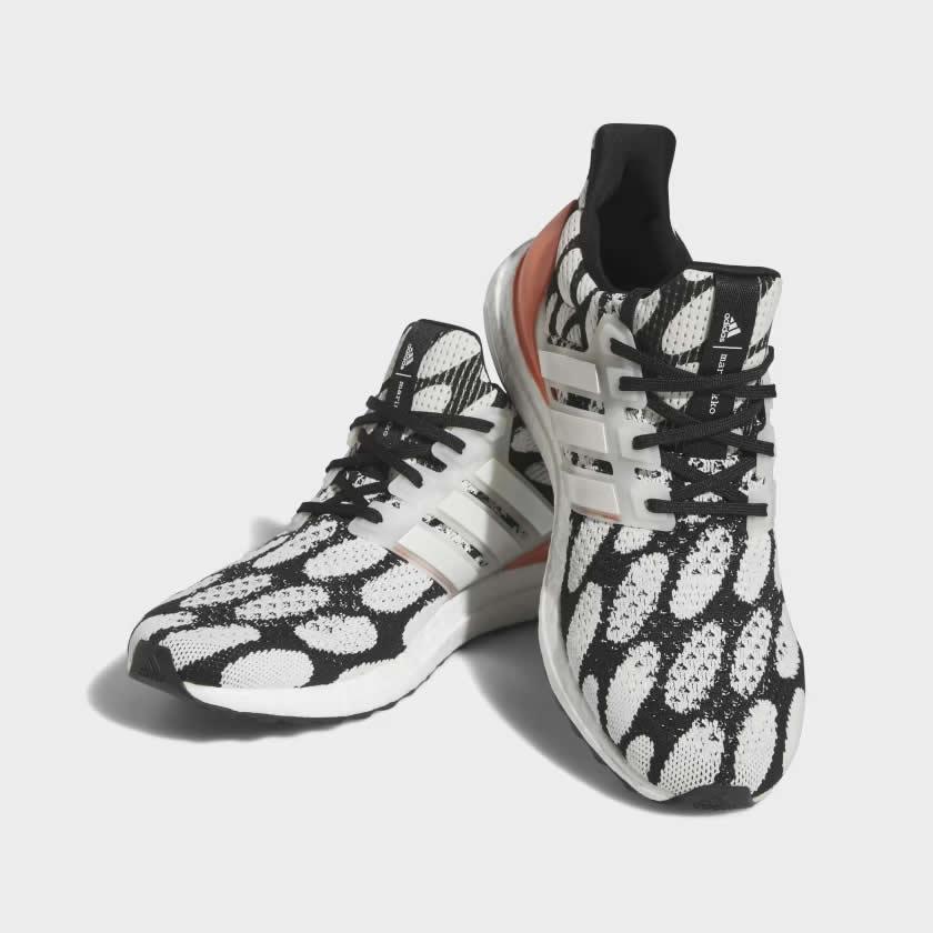 Angled view of two Adidas Ultraboost 1.0 x Marimekko running shoes in black and white with a coral print, side by side, showcasing their bold design.