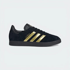 The Core Black Bellingham Gazelle, highlighting the Gold Metallic 3-Stripes and the Jude Bellingham logo on the lateral side.