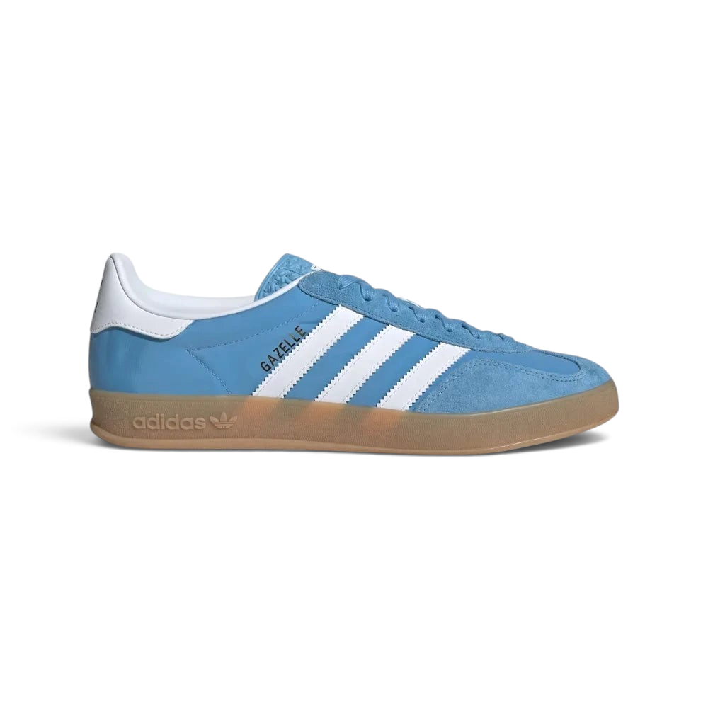 Side Profile Image: The Light Blue Gazelle Indoor, highlighting the Cloud White 3-Stripes and the distinctive translucent gum rubber outsole. Main image