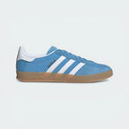 Side Profile Image: The Light Blue Gazelle Indoor, highlighting the Cloud White 3-Stripes and the distinctive translucent gum rubber outsole.