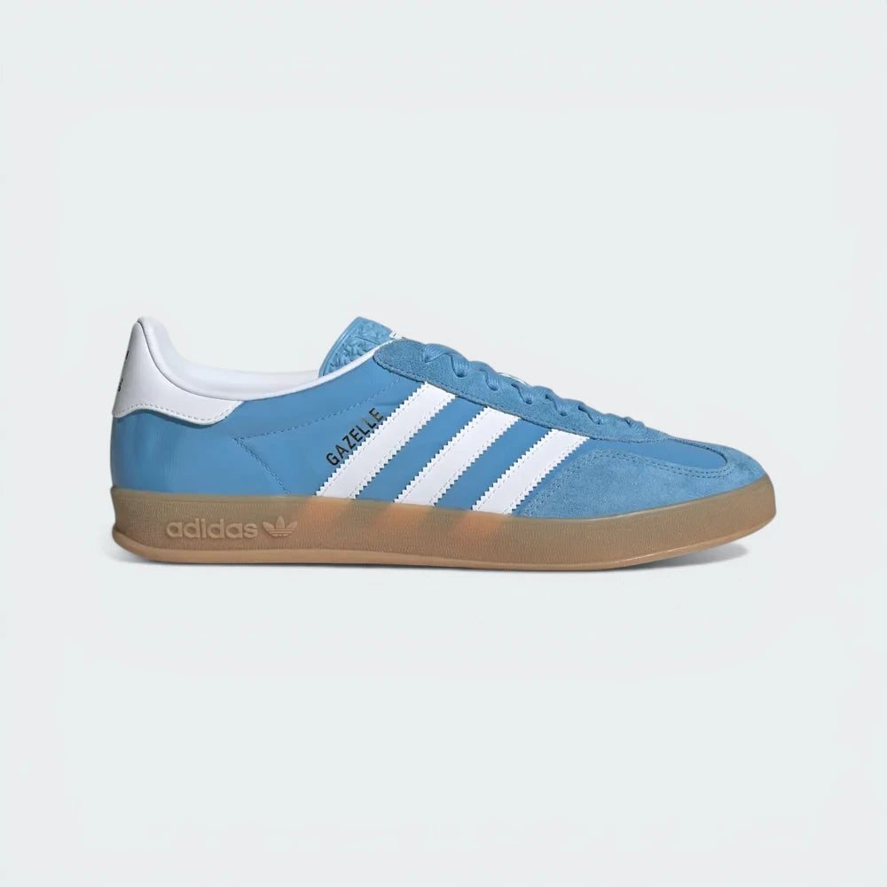 Side Profile Image: The Light Blue Gazelle Indoor, highlighting the Cloud White 3-Stripes and the distinctive translucent gum rubber outsole.