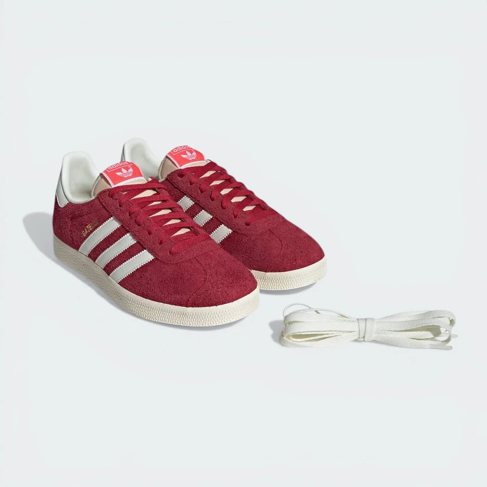 Red Adidas sneakers with white laces on a light gray background