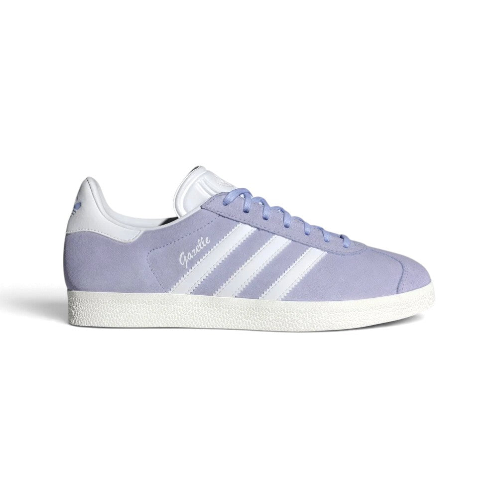 Displays the full lateral silhouette featuring the soft Violet Tone suede upper, contrasting Cloud White serrated 3-Stripes, gleaming metallic gold foil "Gazelle" lettering, matching white heel tab, and the clean rubber cupsole.