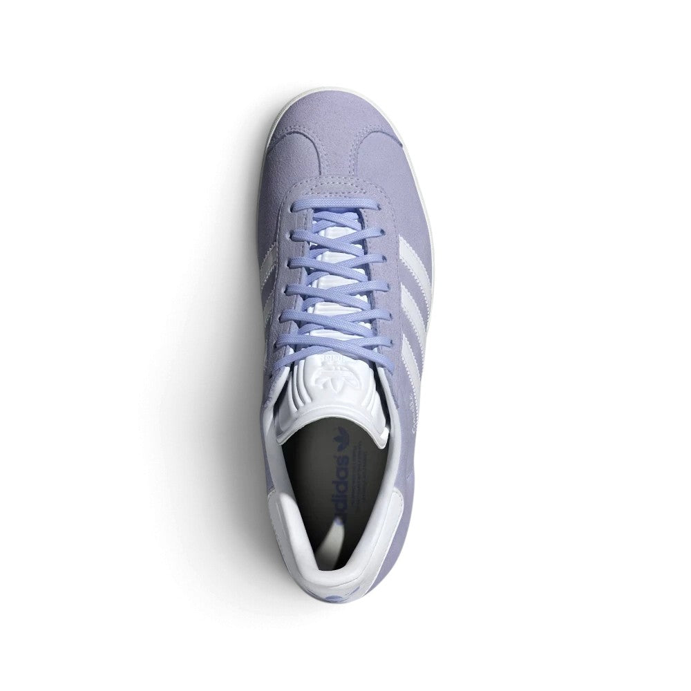 Direct overhead view of the shoe, displaying the classic suede toe overlay, flat violet laces threaded through clean punched eyelets, textured white tongue crowned with the adidas Trefoil logo, and comfortable interior footbed.