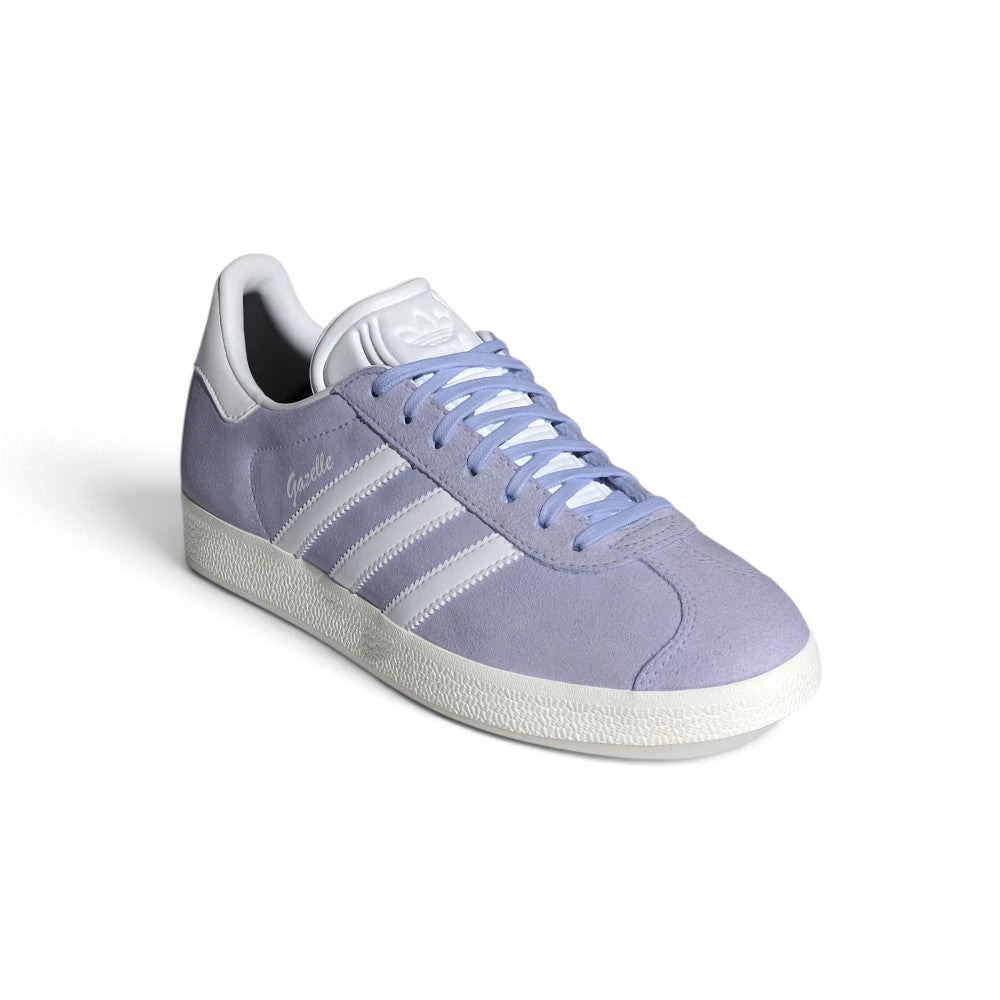 Forward three-quarter angle showcasing the trainer propped up, highlighting the low-slung terrace stance, velvety matte suede texture, flat violet laces, and timeless purple-and-white contrast.