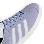 Macro focus on the forefoot, detailing the fine velvety nap of the Violet Tone suede, classic T-toe stitch contour, and flat violet laces passing through clean punched eyelets.