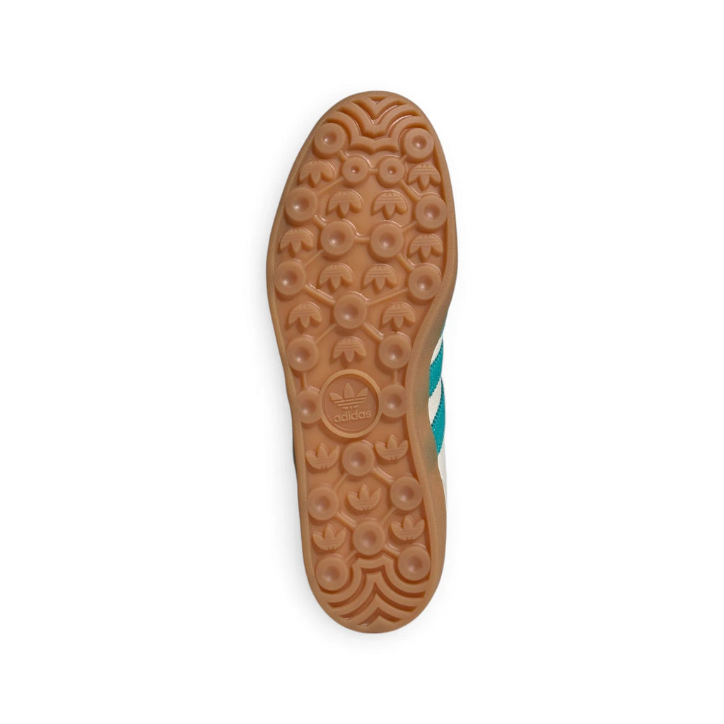 Bottom-down view of the amber gum rubber outsole, showcasing the iconic tread pattern featuring repeating trefoil motifs and pivot circles.
