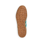 Bottom-down view of the amber gum rubber outsole, showcasing the iconic tread pattern featuring repeating trefoil motifs and pivot circles.