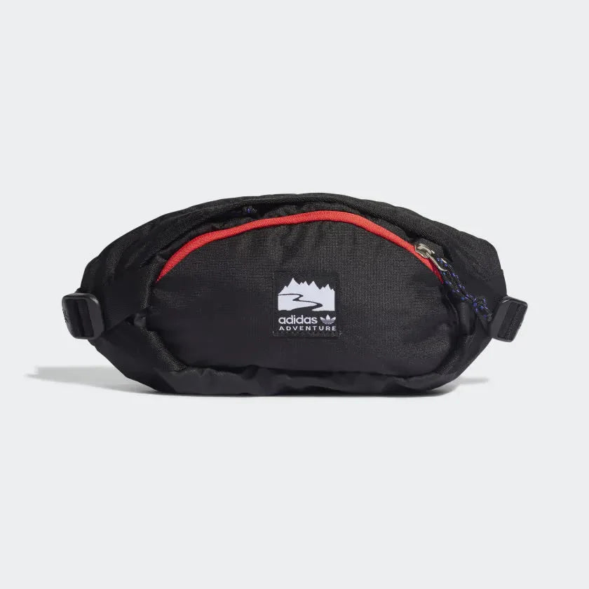 Adidas Adventure Waist Bag in black with bright red and white accents, front view showing main zip pocket, front zip pocket, and woven Adidas brand patch. Main image