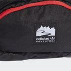Close-up zoom on the Adidas Adventure Waist Bag in black, showing the ripstop fabric texture and the woven Adidas patch on the front with its detailing.