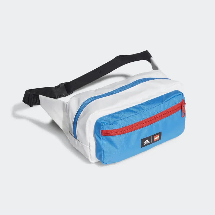 A junior's Adidas waist bag in white, blue, and black with a LEGO color scheme, featuring a front zip pocket and an adjustable waist strap with a buckle closure.