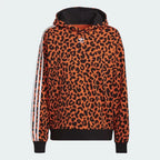 Adidas x Rich Mnisi Hoodie Women's in a true orange and black animal print, front view showing the drawcord hood and kangaroo pocket.