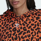 Close-up zoom on the fabric of the Adidas x Rich Mnisi Hoodie, showing the soft French terry texture and the detailed orange and black animal print.