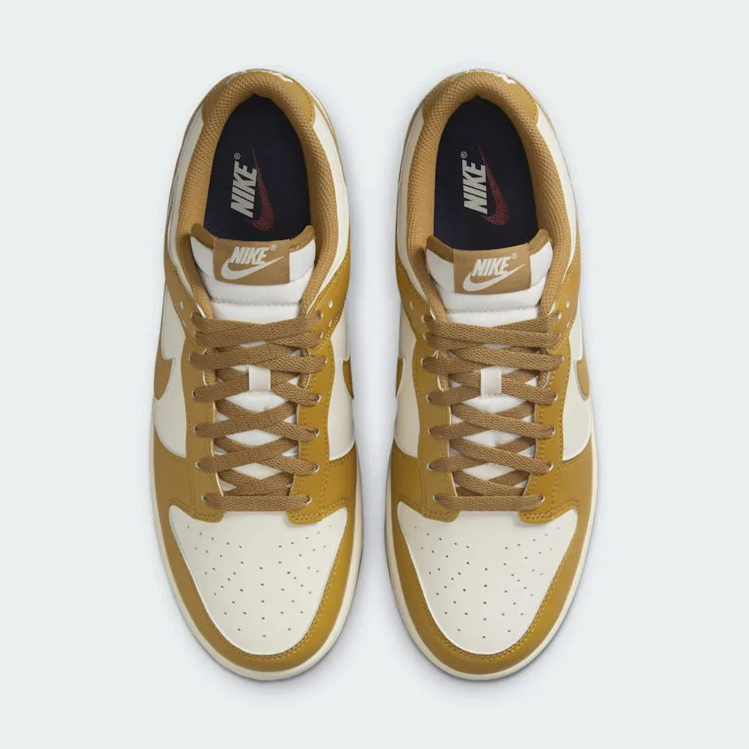 Top-down view of a pair of Nike Dunk Low Retro Men's trainers in wheat, highlighting their iconic silhouette and lace-up closure.