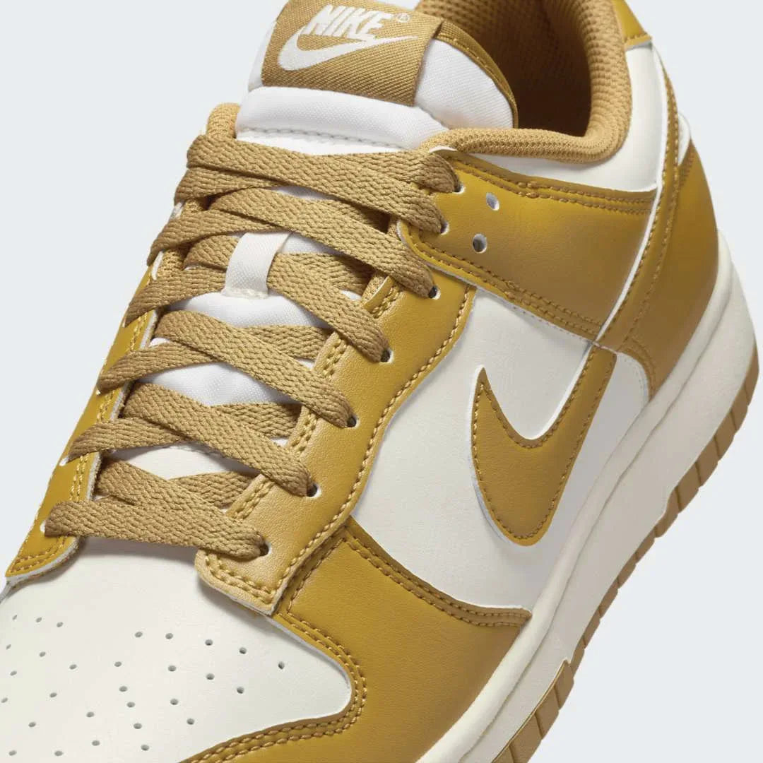 Close-up zoom on the front of the Nike Dunk Low Retro Men's wheat trainers, showing the perforated toe box, lace-up system, and textured leather upper.