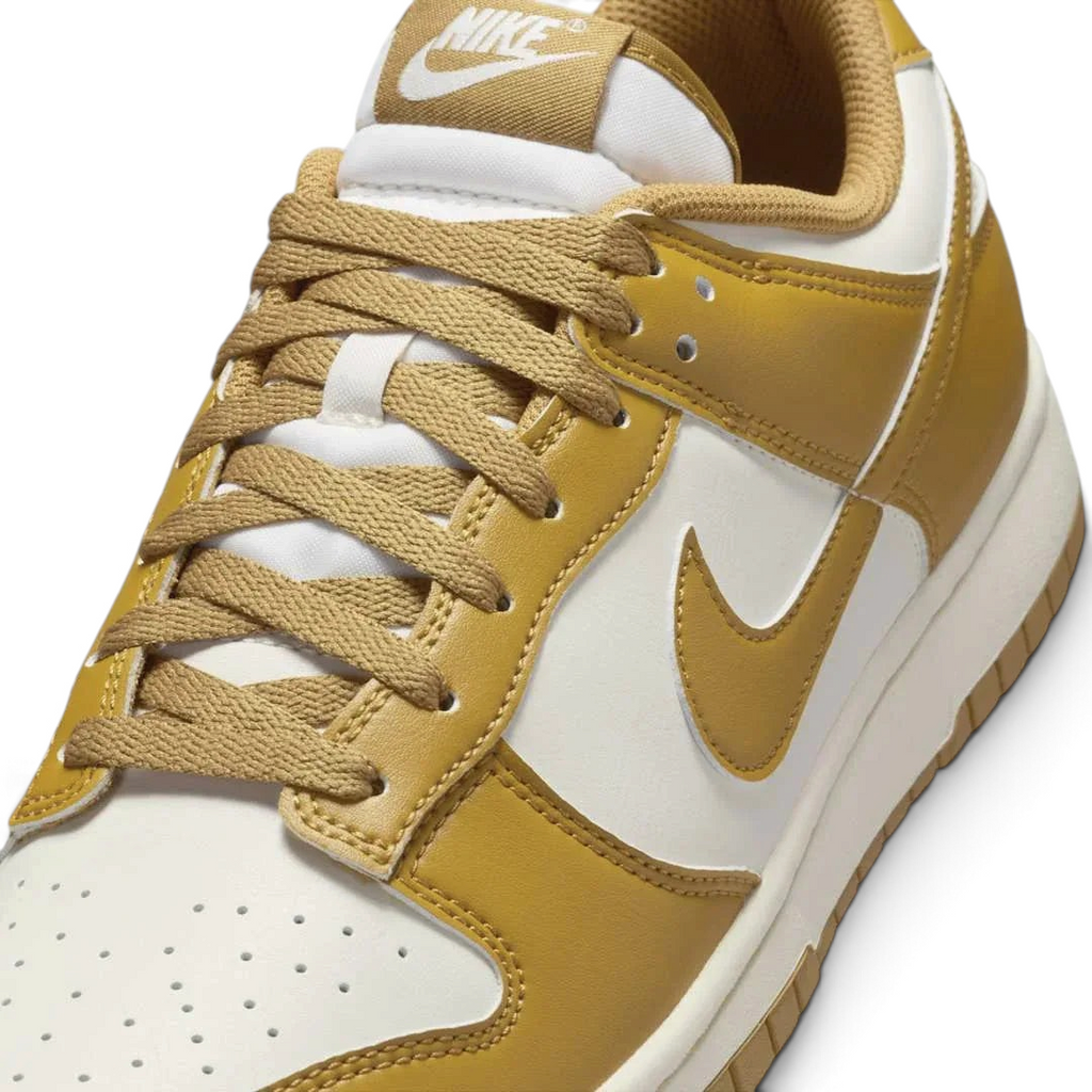 Close-up zoom on the front of the Nike Dunk Low Retro Men's wheat trainers, showing the perforated toe box, lace-up system, and textured leather upper.