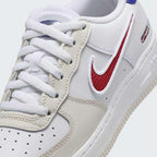 Close-up zoom on the front of the Nike Air Force 1 LV8 Juniors' white trainers, showing the perforated toe box, lacing system, and texture of the leather upper.