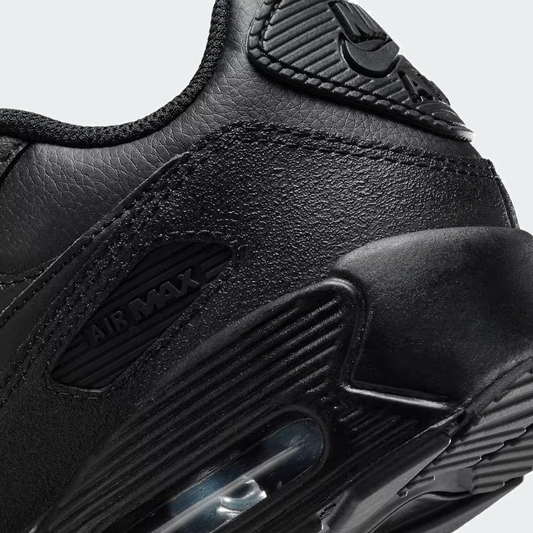 Detailed zoom on the outsole and midsole of the Nike Air Max 90 Juniors' black trainers, highlighting the cushioned foam and visible Max Air unit.