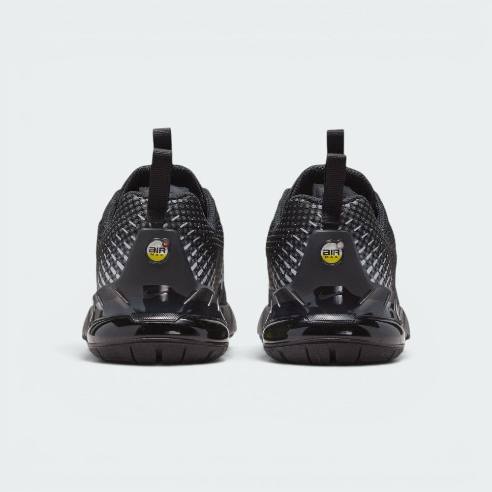 Focuses on the rear profile, highlighting the dual black pull tabs, circular yellow-and-black "AIR MAX" badges, and the translucent black heel clip framing the yellow Air bubble.