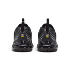 Focuses on the rear profile, highlighting the dual black pull tabs, circular yellow-and-black "AIR MAX" badges, and the translucent black heel clip framing the yellow Air bubble.