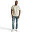 Man wearing a beige t-shirt and blue jeans on a white background