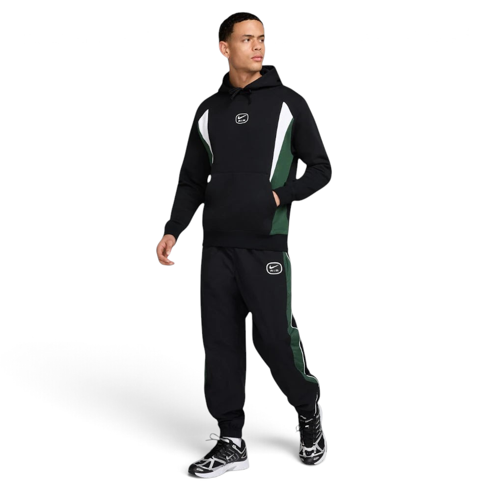 Man wearing a black and green tracksuit with brand logos on a white background