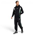 Man wearing a black and green tracksuit with brand logos on a white background