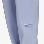 Close-up zoom on the Adidas Trefoil Linear Sweat Pants in violet, showing the soft fleece fabric texture and the detailed linear Trefoil logo print on the leg.