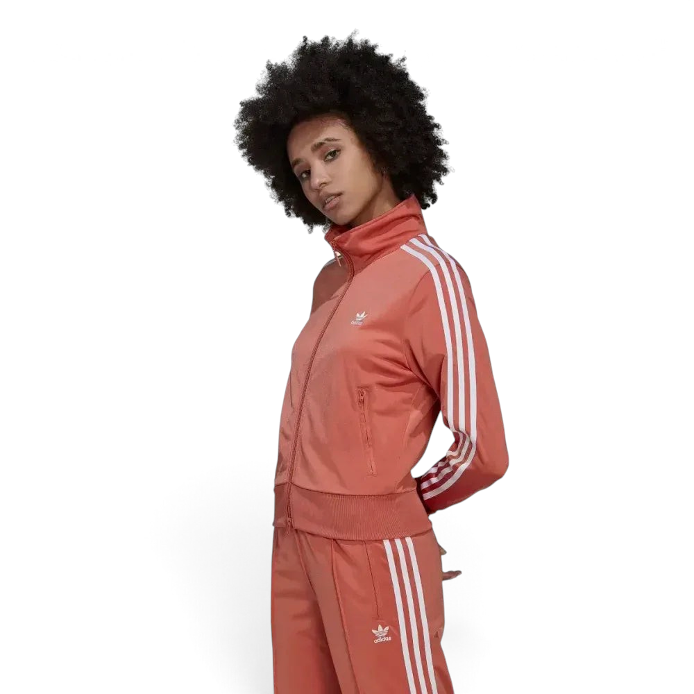 Side profile of the Adidas Firebird track top in Magic Earth brown, showing the classic white 3-Stripes running from the shoulder to the ribbed cuff.