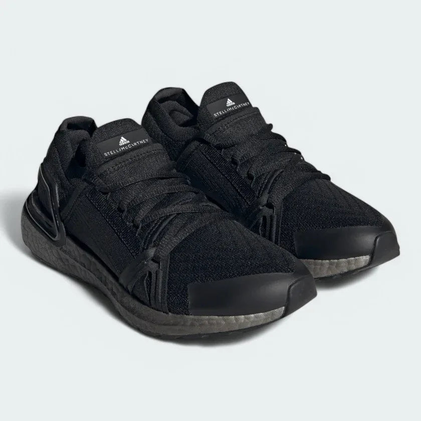 Angled view of two Adidas by Stella McCartney Ultra Boost 20 Women's trainers in black, side by side, showcasing their bold design and fashion-forward silhouette.