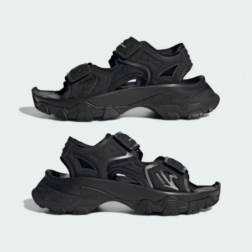 Angled view of two Adidas by Stella McCartney Hika Sandals in black, side by side, showcasing their robust yet stylish design.