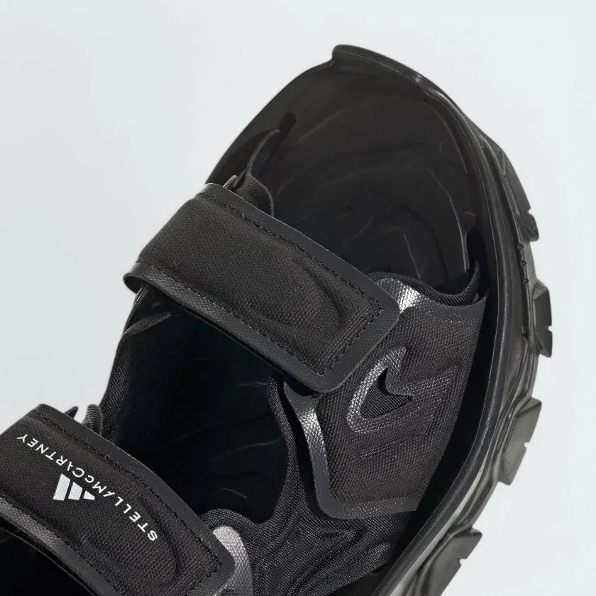 Close-up zoom on the straps of the Adidas by Stella McCartney Hika Sandal, showing the texture of the material and the collaborative Adidas by Stella McCartney logo.