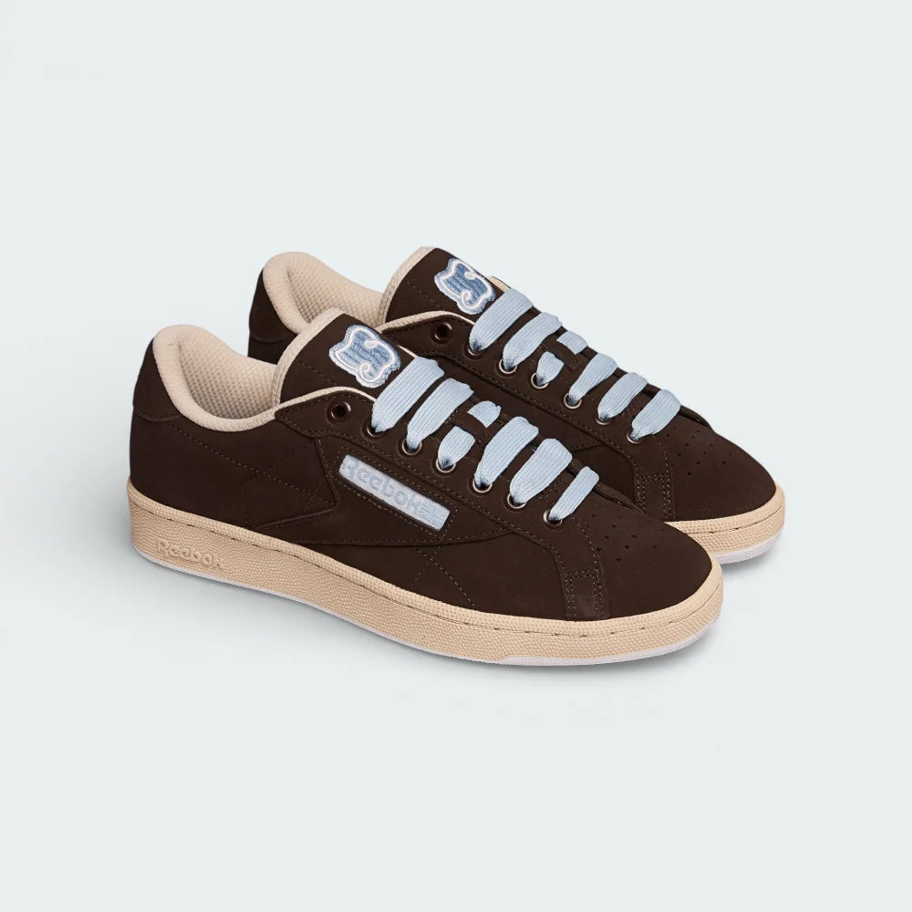 Angled shot of both Reebok x SNEEZE trainers side by side, showcasing the minimalist earthy aesthetic and the clean, low-profile silhouette.