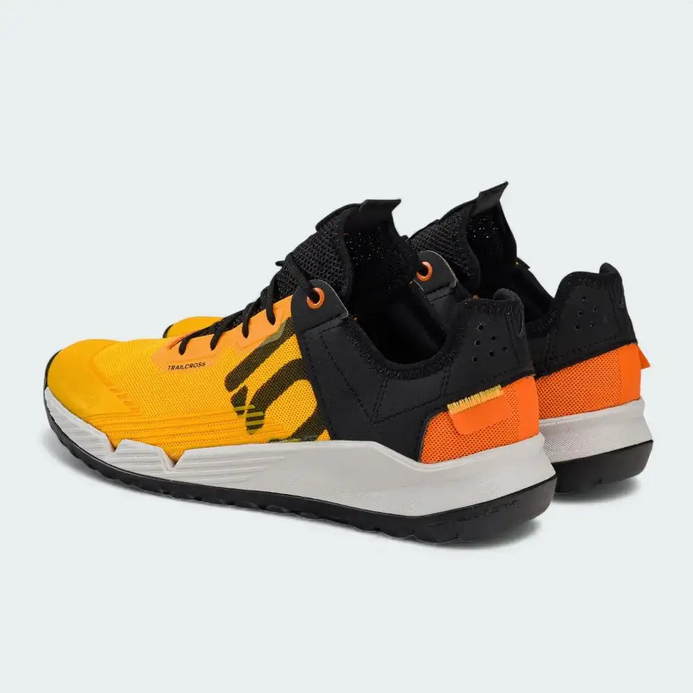 Pair of black, orange, and yellow sneakers on a light gray background