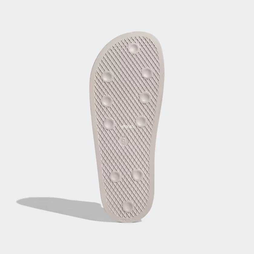 View of the outsole of the Adidas Adilette Slides Unisex in pink, showing the durable rubber sole and textured tread pattern.